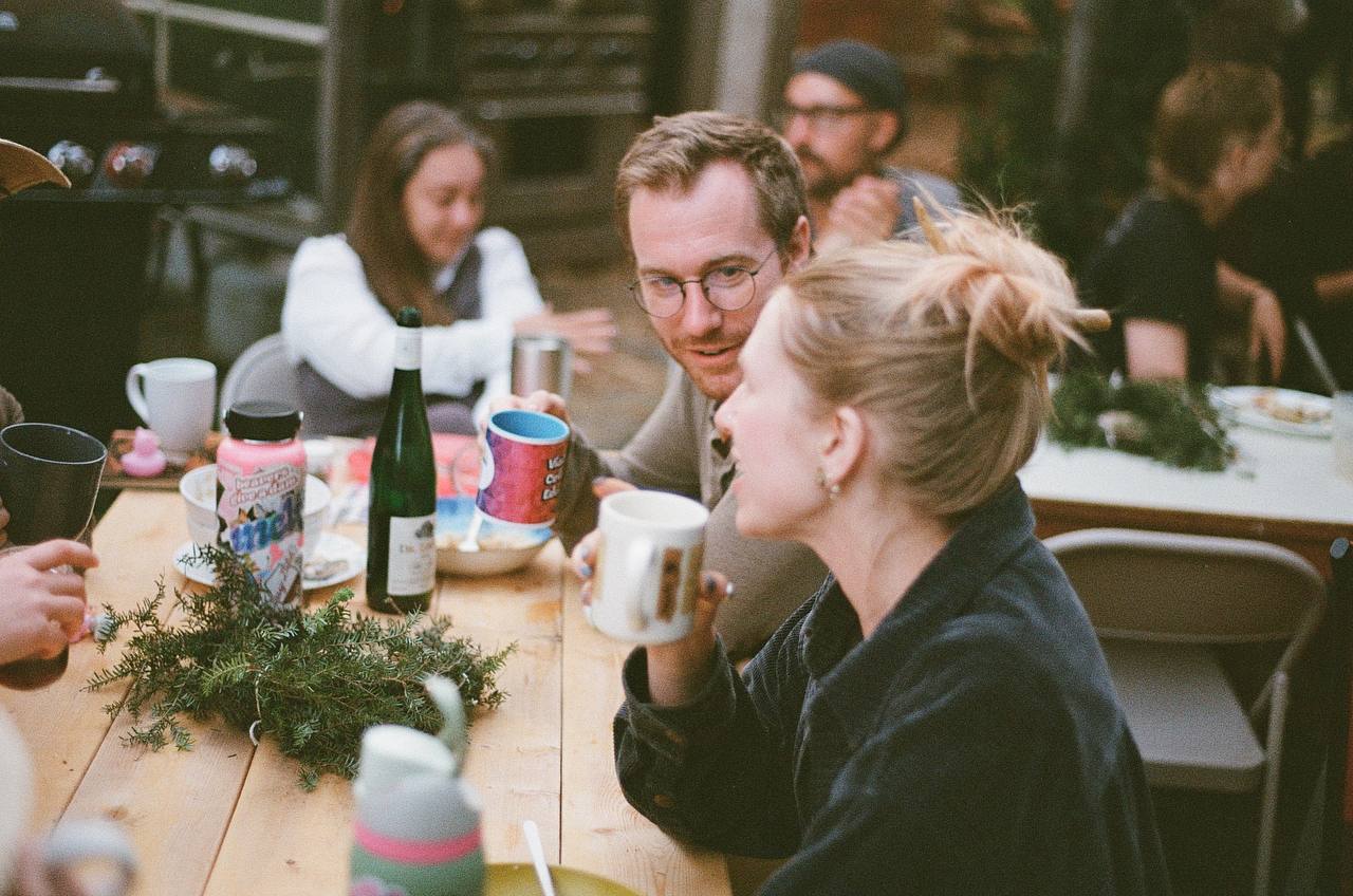 Attendees drink coffee together around a wooden table.